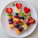 Close-up of Berry Good Heart Fruit Skewers with fresh berries and melon hearts, ready to eat.