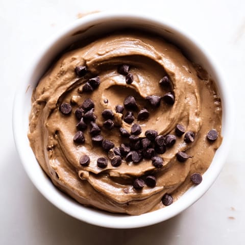 Rich chocolate hummus, the perfect healthy snack, pictured with crunchy pretzel sticks and sliced apples.