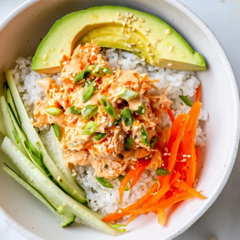 Flaky spicy canned salmon atop fluffy rice in this delicious rice bowl, served with fresh veggies.