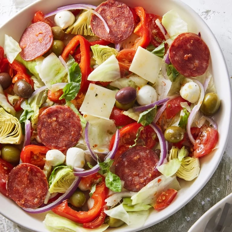 Close-up of a vibrant Antipasto Chickpea Salad, showcasing pepperoni and a tangy vinaigrette dressing.