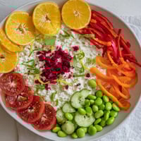 A colorful The Prism Burst salad showcases fresh vegetables and fruits in vibrant layers.